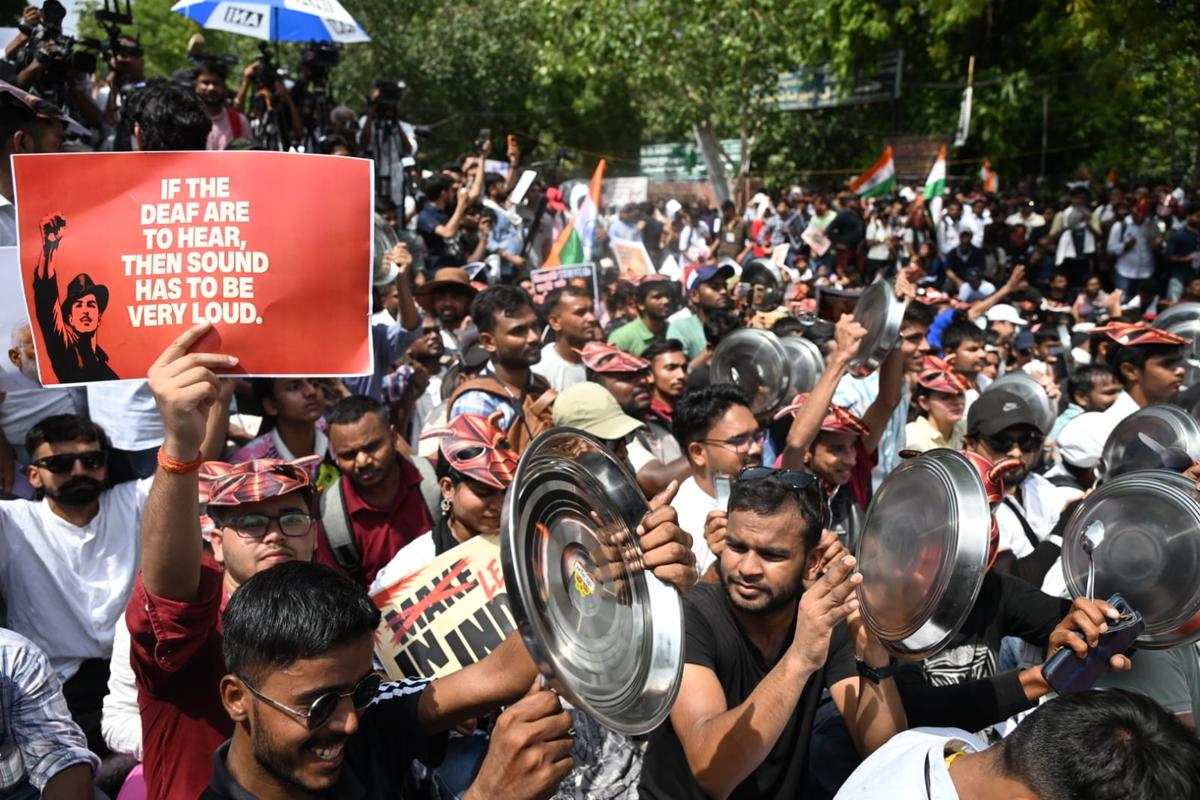 Protesters at Jantar Mantar holding posters of Bhagat Singh, one reading a quote about the deaf needing to hear a loud sound